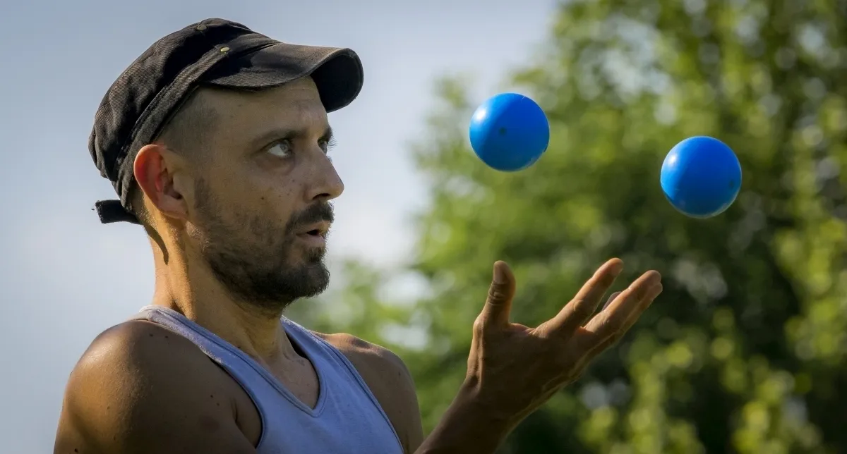 Juggler watching two blue balls rise above his open hand